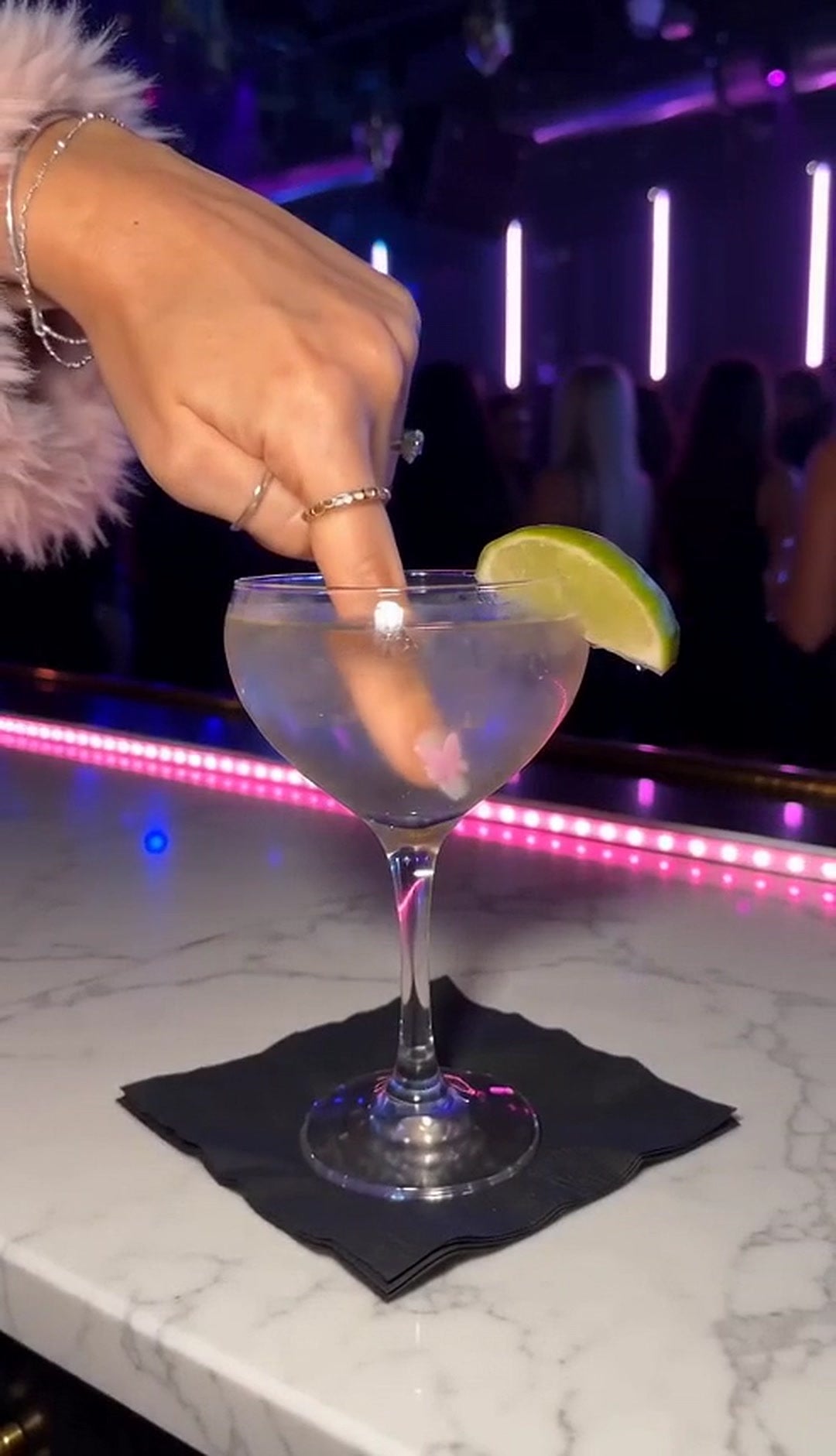 Dipping a stickered fingertip into a cocktail at the bar